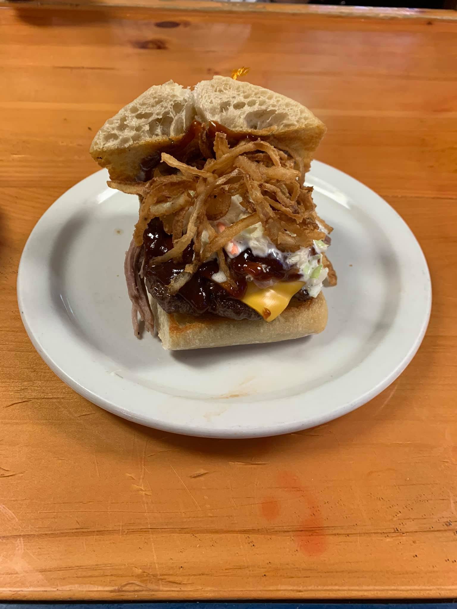 Burger topped with BBQ sauce, crispy onion straws, coleslaw and cheese